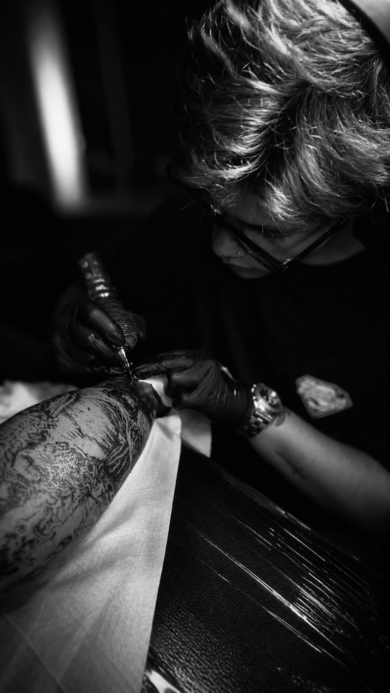 Tatuador concentrado sombreando un brazo