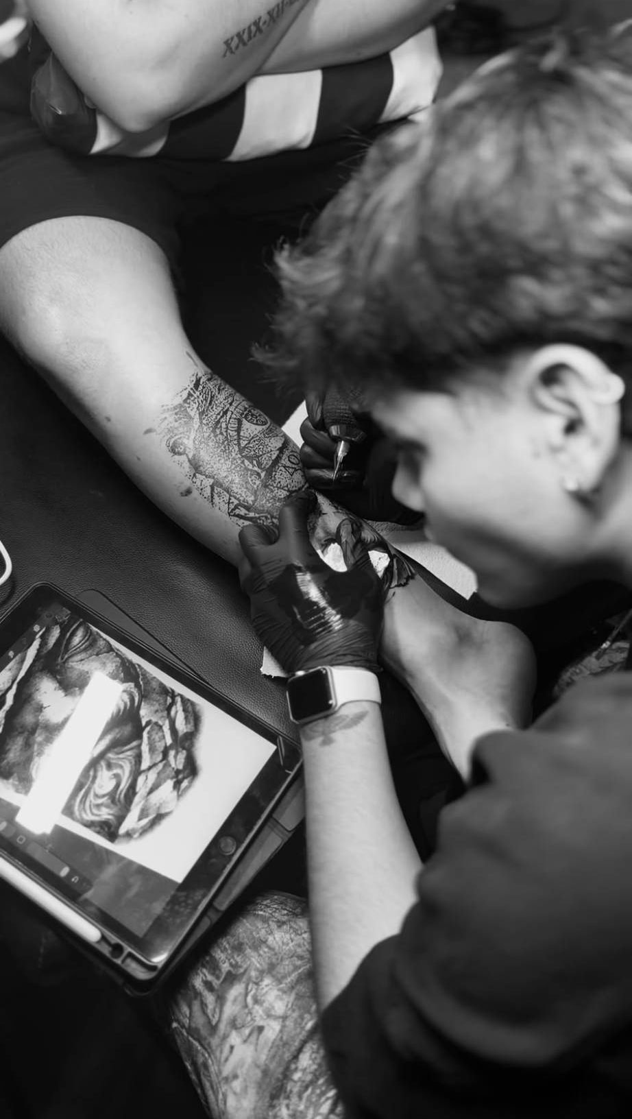 Manu tatuando un antebrazo con el diseño en la tableta